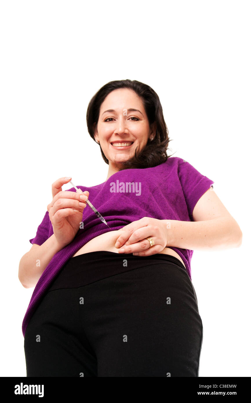 Attractive happy diabetic woman injecting insulin in her belly for