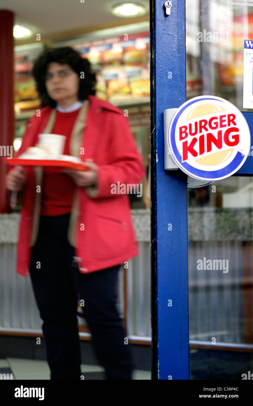 A female Burger King customer find a place to sit and eat Stock Photo