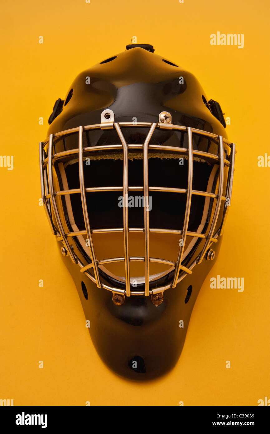 a black hockey goalie helmet on a gold background. some scratches and