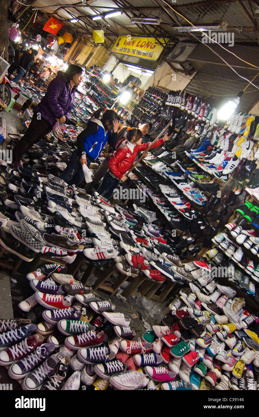 Vertical wide angle of hundreds of pairs of shoes on sale on Hang Dau street in the centre of the Old Quarter in Hanoi. Stock Photo