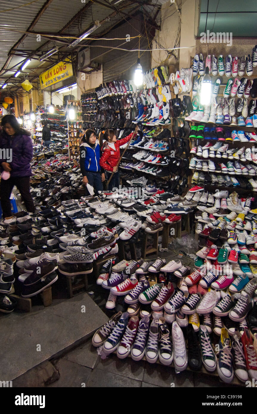 Vertical wide angle of hundreds of pairs of shoes on sale on Hang Dau street in the centre of the Old Quarter in Hanoi. Stock Photo