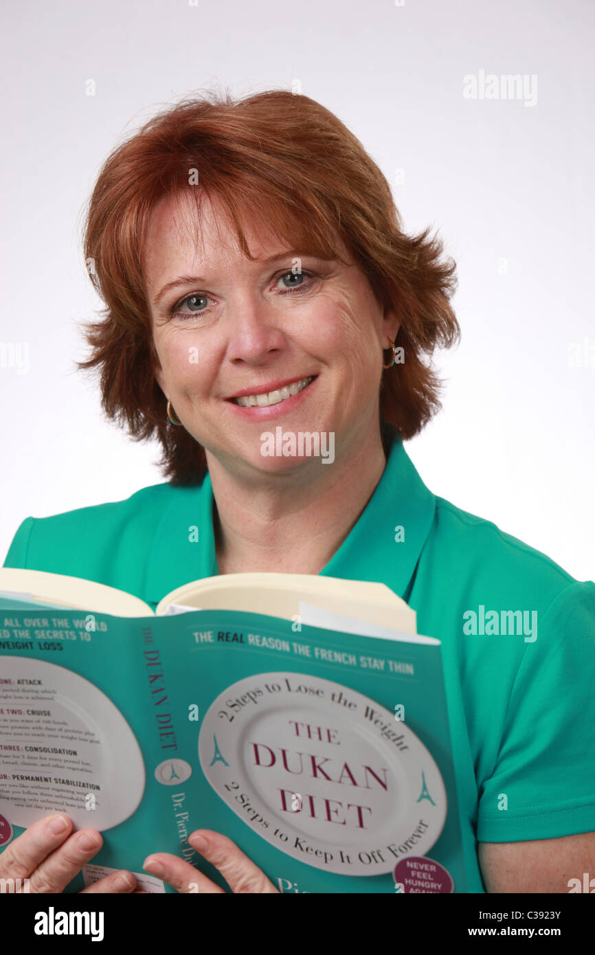 Attractive middle-aged American woman reading The Dukan Diet book, white background, studio shot, April 20, 2011, © KAndriotis Stock Photo