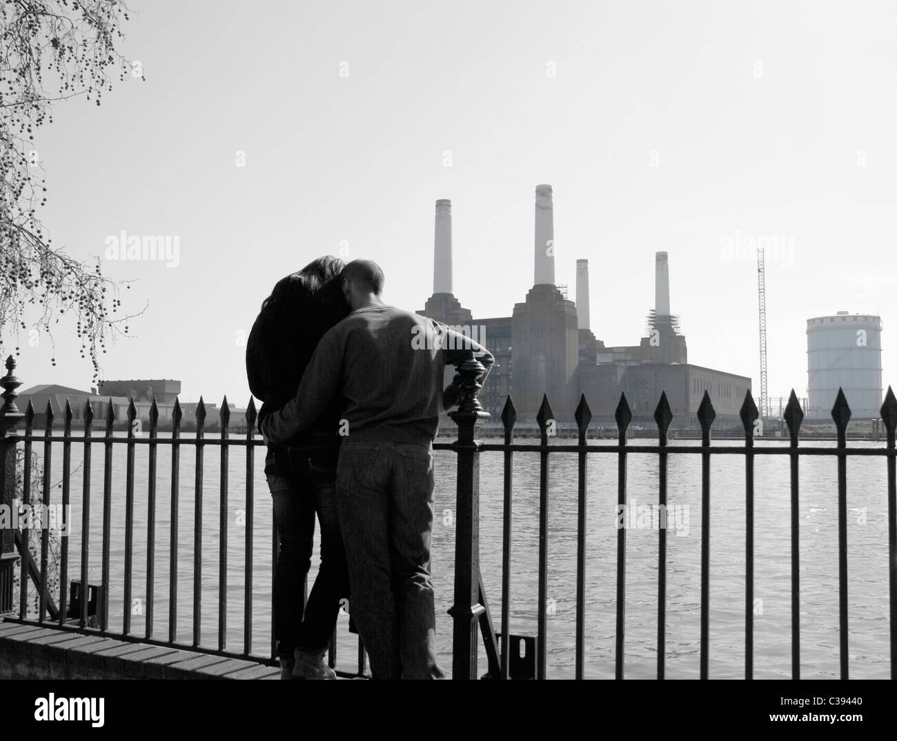 Anonymous couple on the Thames Embankment overlooking Battersea Power Station. Stock Photo