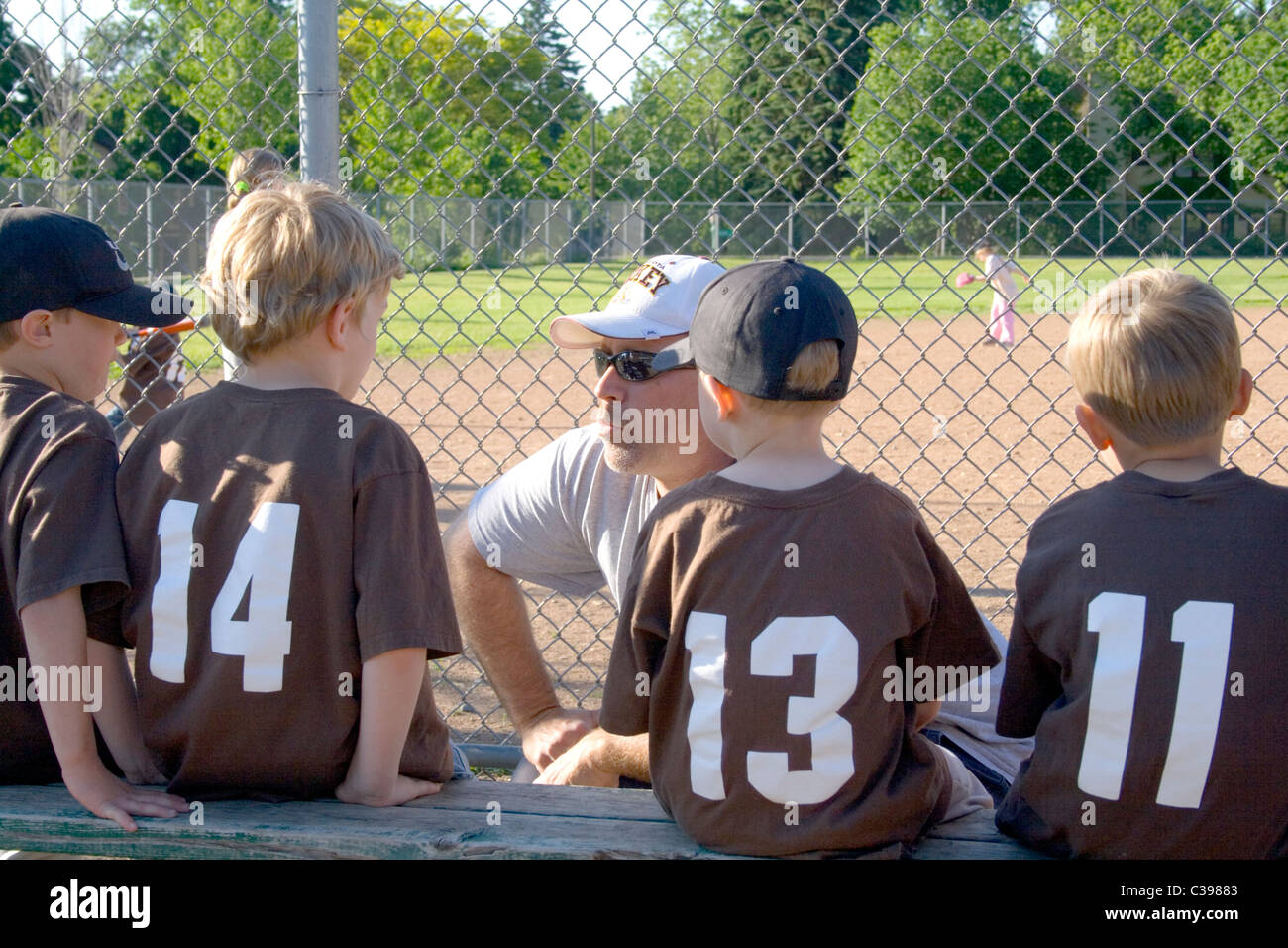 Coach speaking instructing young baseball players on the bench. St Paul