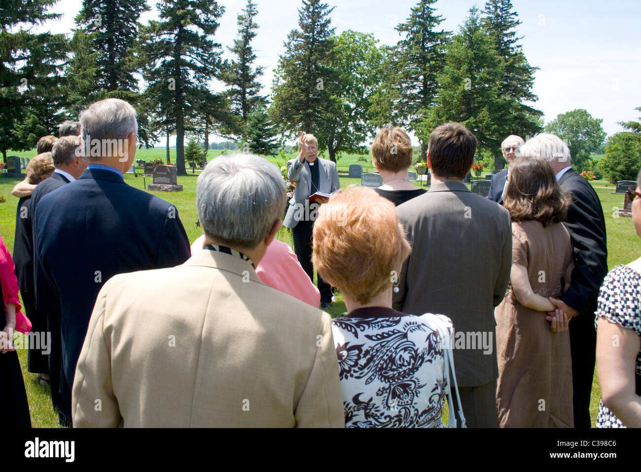 Minister performing graveside committal at a funeral before friends and