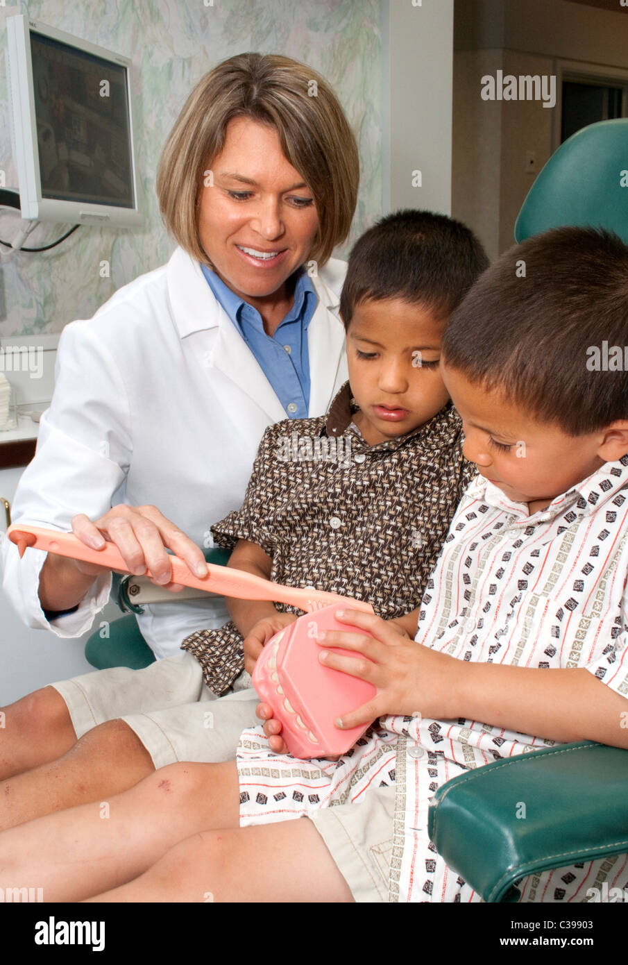 Dental hygienist helping patients boys age 7 brush teeth correctly. St