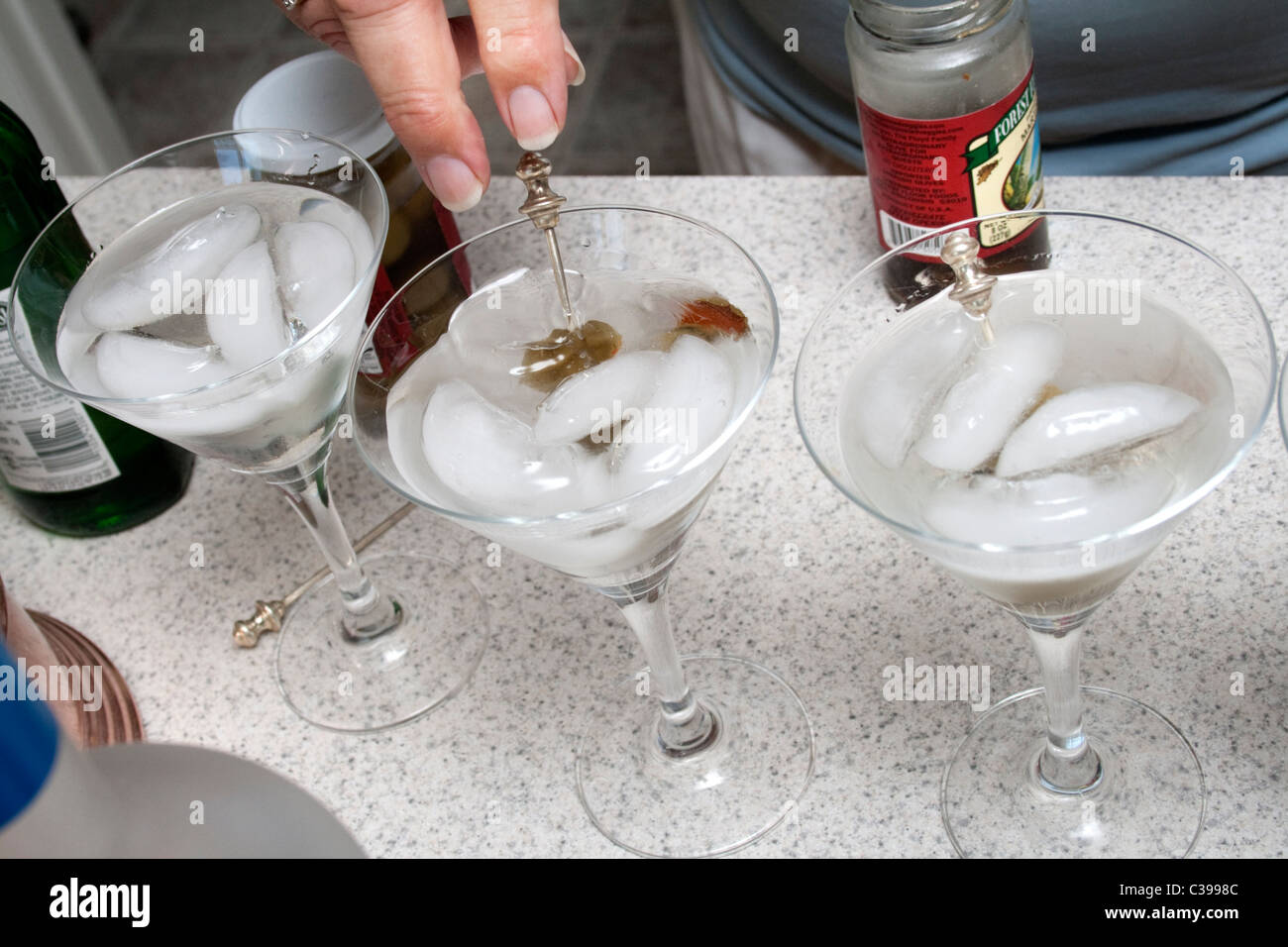 Bartender adding olives to stemmed martini glasses. St Paul Minnesota MN USA Stock Photo