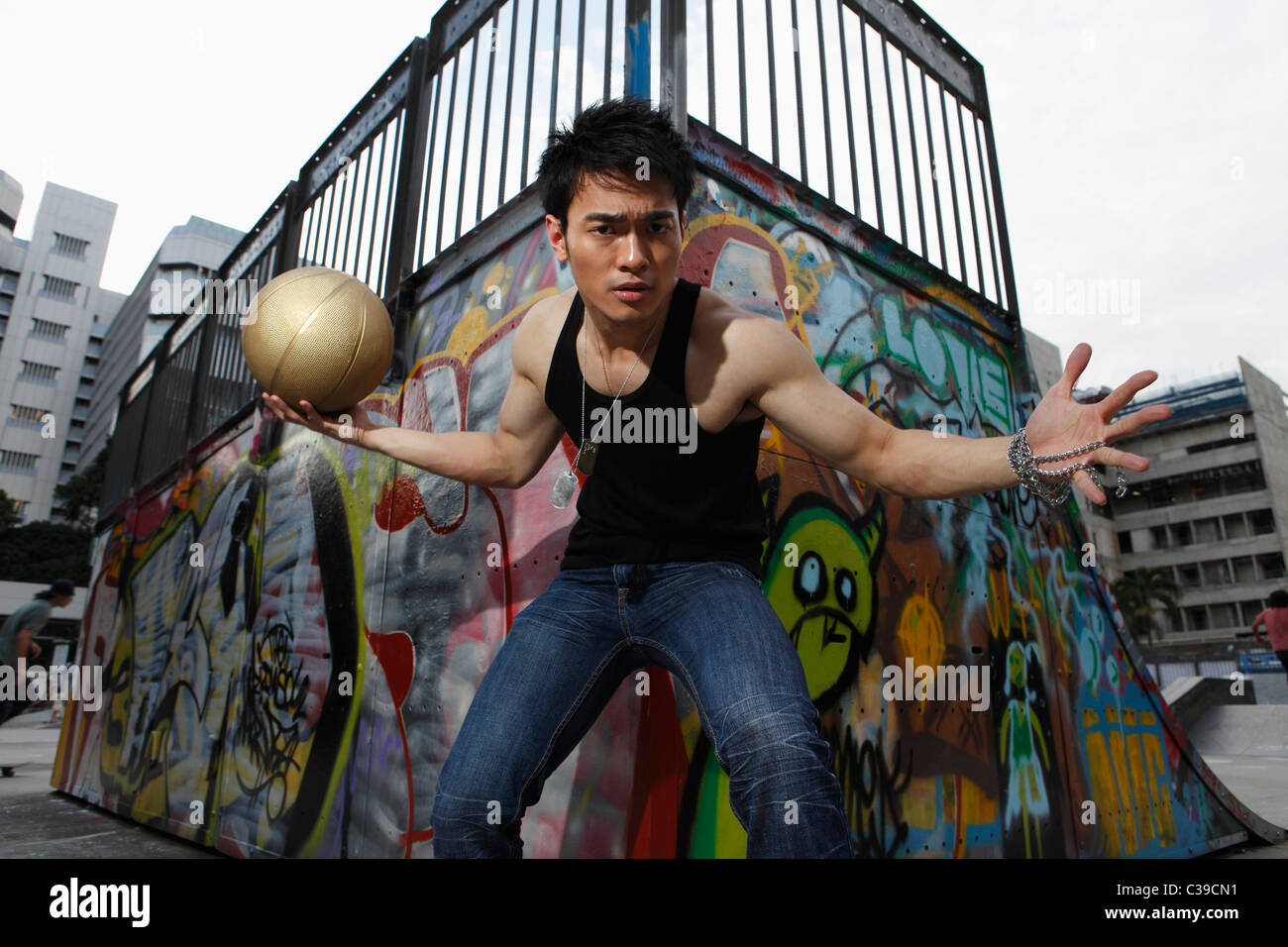 Young man playing basketball outside in urban park Stock Photo