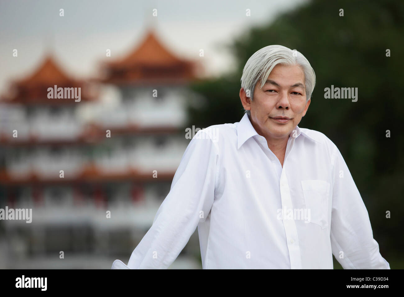 Older man standing outside in front of pagodas Stock Photo