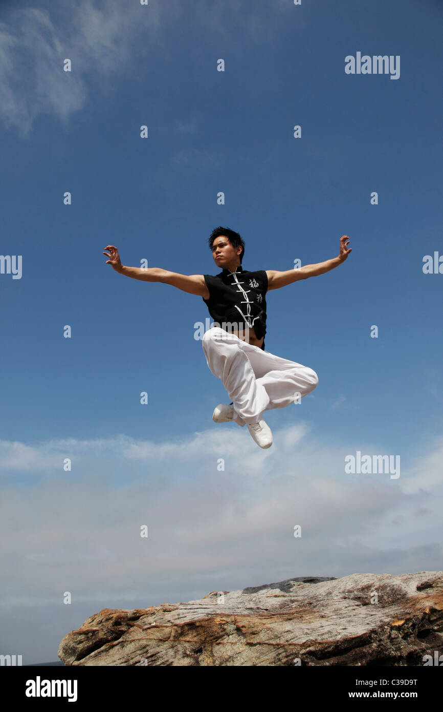 Chinese man jumping in air while doing a martial arts pose Stock Photo