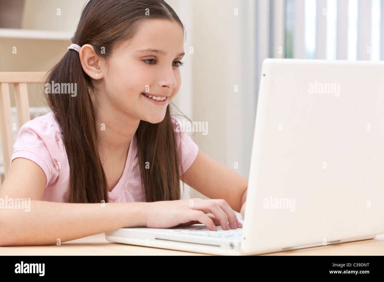 A young girl child smiling and using laptop computer at home Stock ...