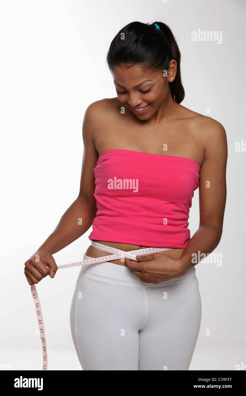 Young woman measuring herself with tape measure and smiling Stock Photo