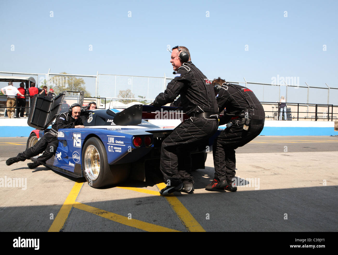 Pit crew pulling group C car back into the pit garage Stock Photo