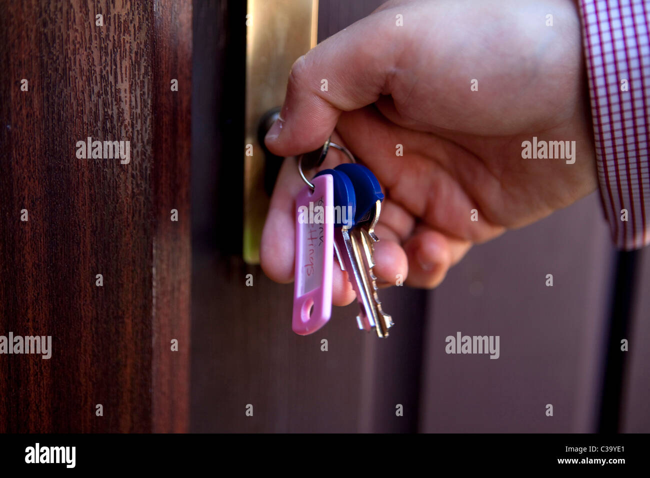 Hand holding keys opening a door Stock Photo - Alamy