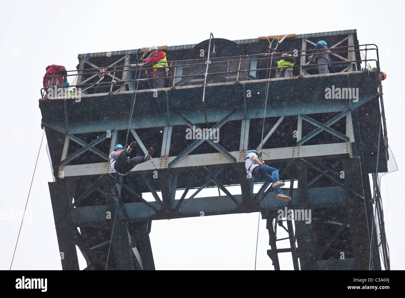 Two people completing a charity abseil in the rain, from the Finnieston Crane, Stobcross Glasgow. Scotland, UK. Stock Photo