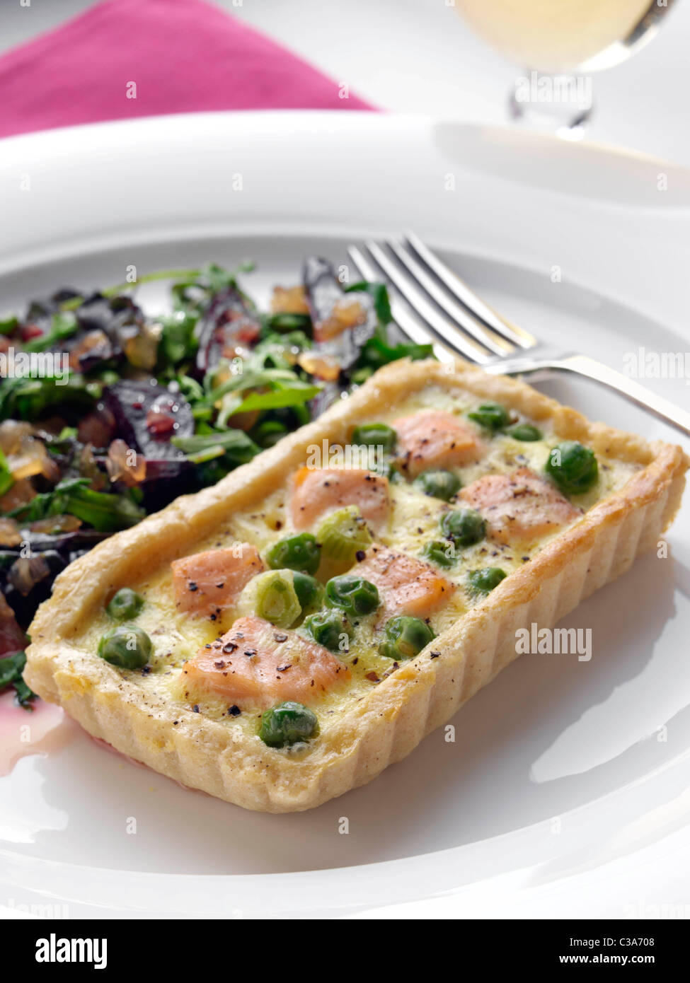 Individual salmon quiche with roasted baby beetroot leaves Stock Photo