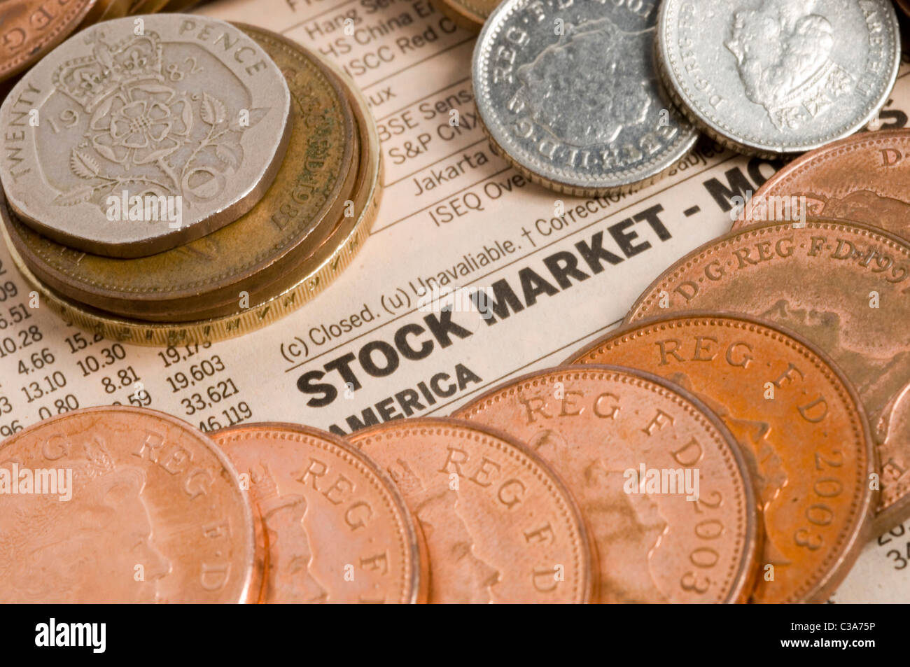 Various coins pictured on top of a stock markets newspaper page. Stock Photo