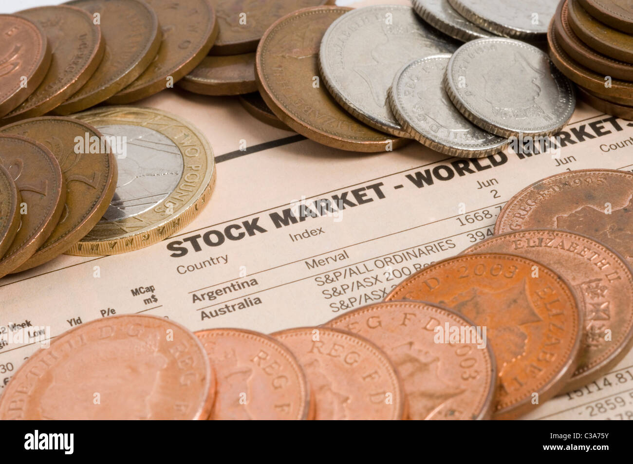 Various coins pictured on top of a stock markets newspaper page. Stock Photo