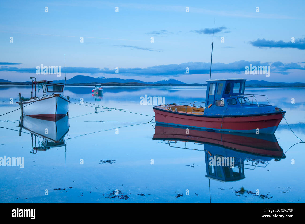 Fishing boats reflected at dusk in Clew Bay, County Mayo, Ireland. Stock Photo