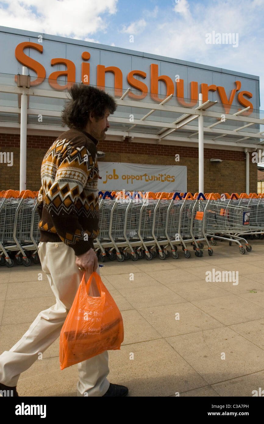 A customer passing the outside of a Sainsbury's store Stock Photo Alamy
