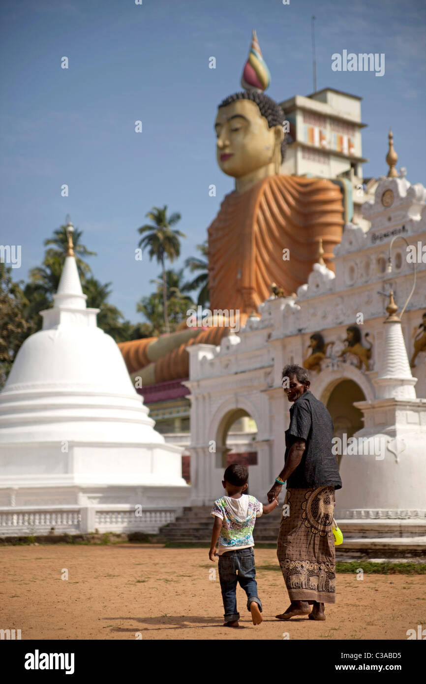 grandfather and child at Sri Lankas biggest Buddha Statue at Wewurukannala Vihara Temple near Dikwella, Pussalagoda, Sri Lanka, Stock Photo