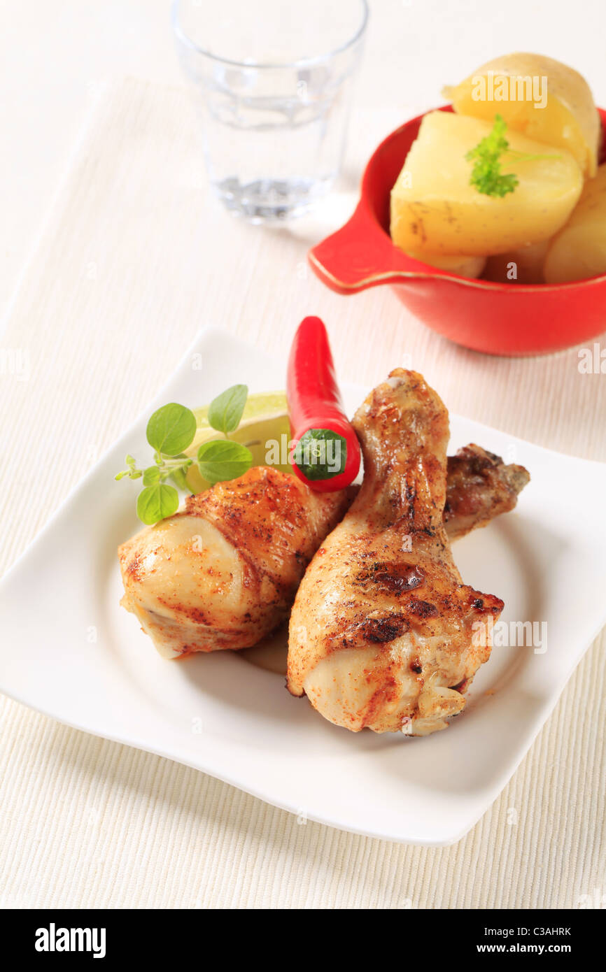 Spicy roast chicken drumsticks and new potatoes Stock Photo