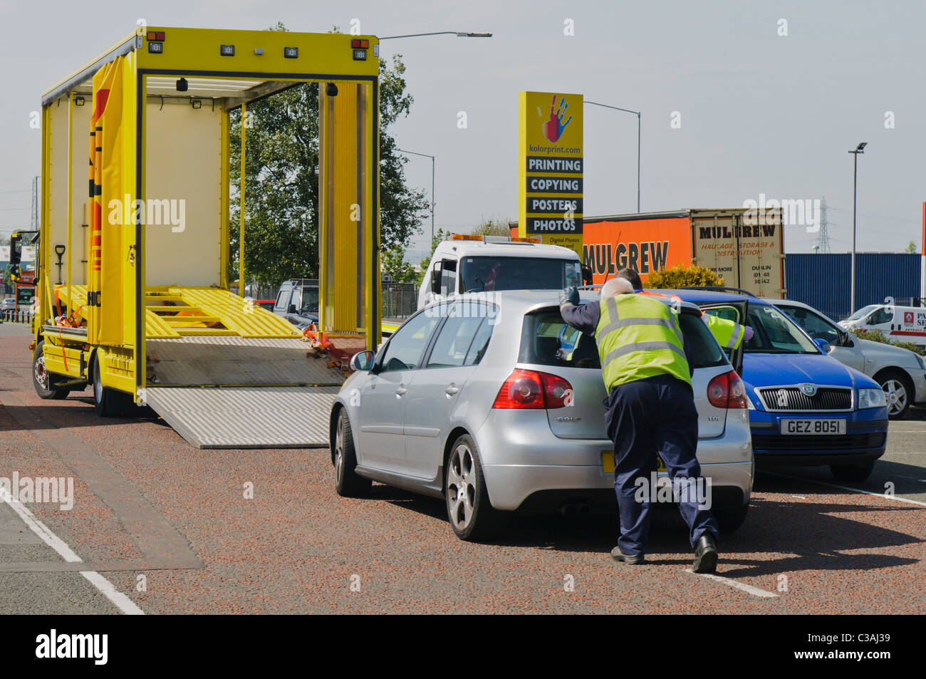 Silver Volkswagen Golf is pushed onto a recovery truck Stock Photo