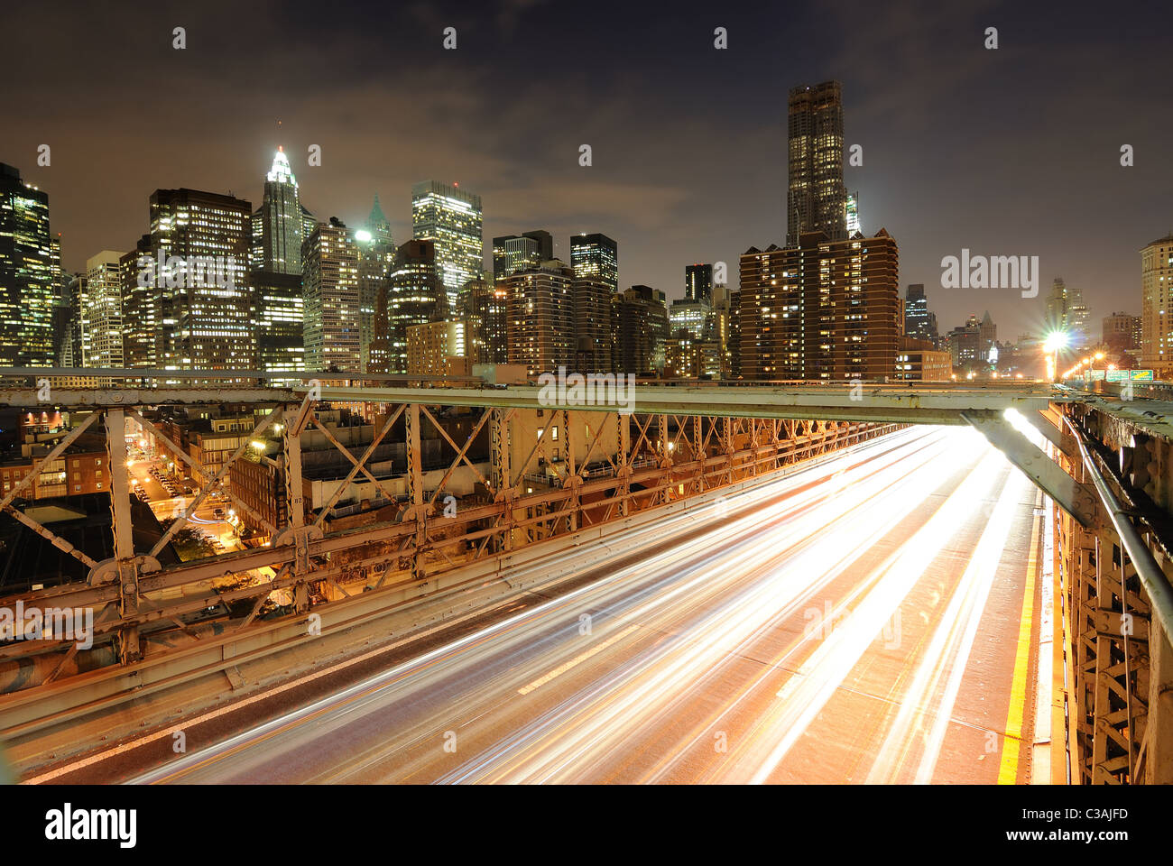 View of downtown Manhattan from the Brooklyn Bridge with traffic flying by. Stock Photo