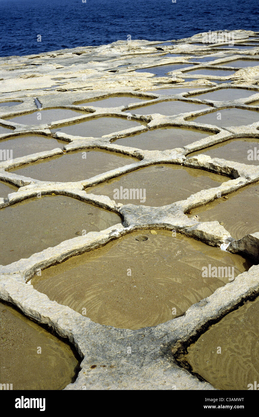 Salt evaporation pans cut into sandstone by the Mediterranean Sea at Xwejni Bay on the Maltese island of Gozo. Stock Photo