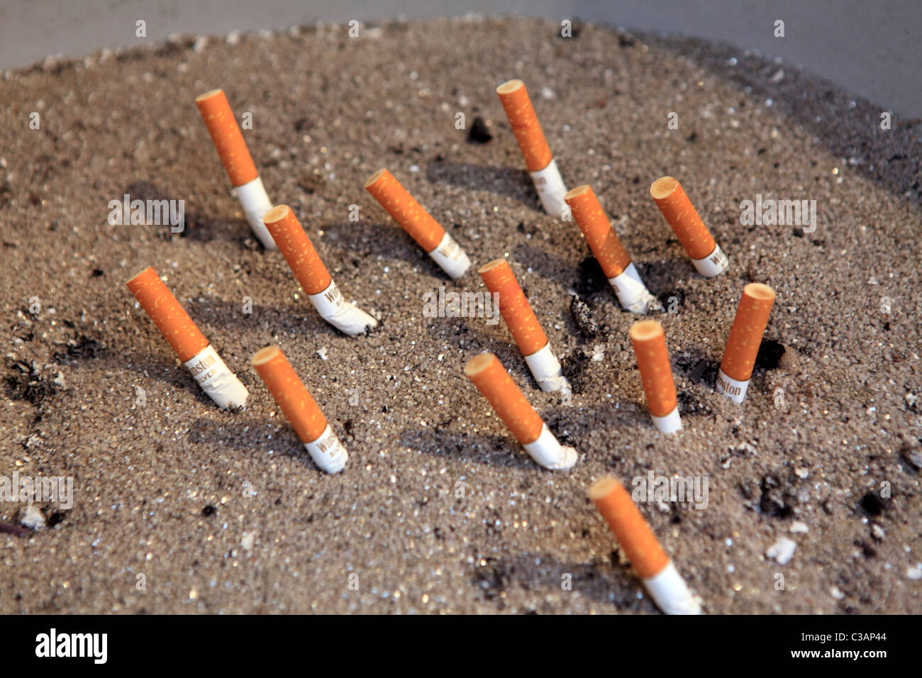 Cigarette ends stubbed out in sand Stock Photo