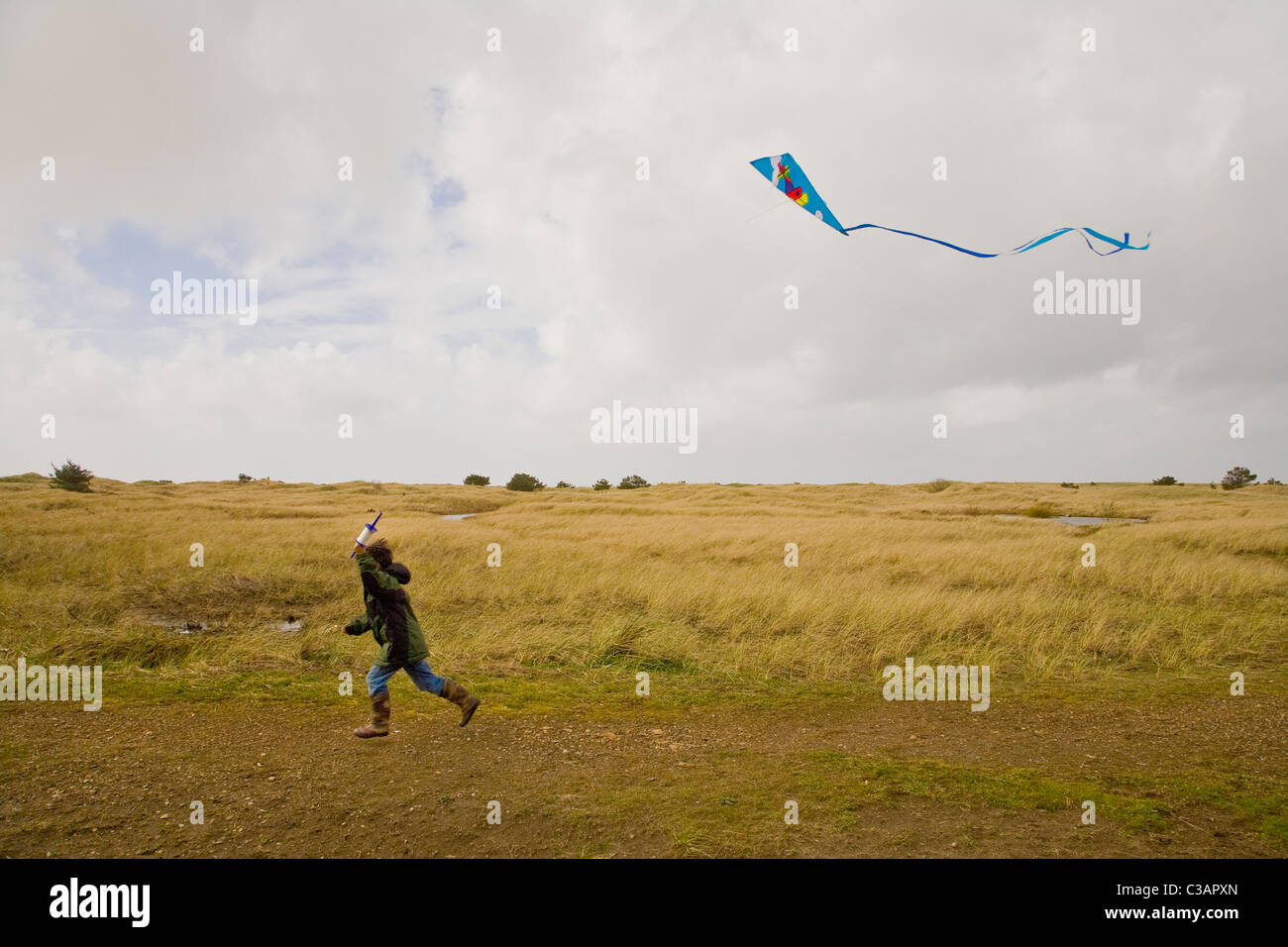 boy running with kite in air Stock Photo