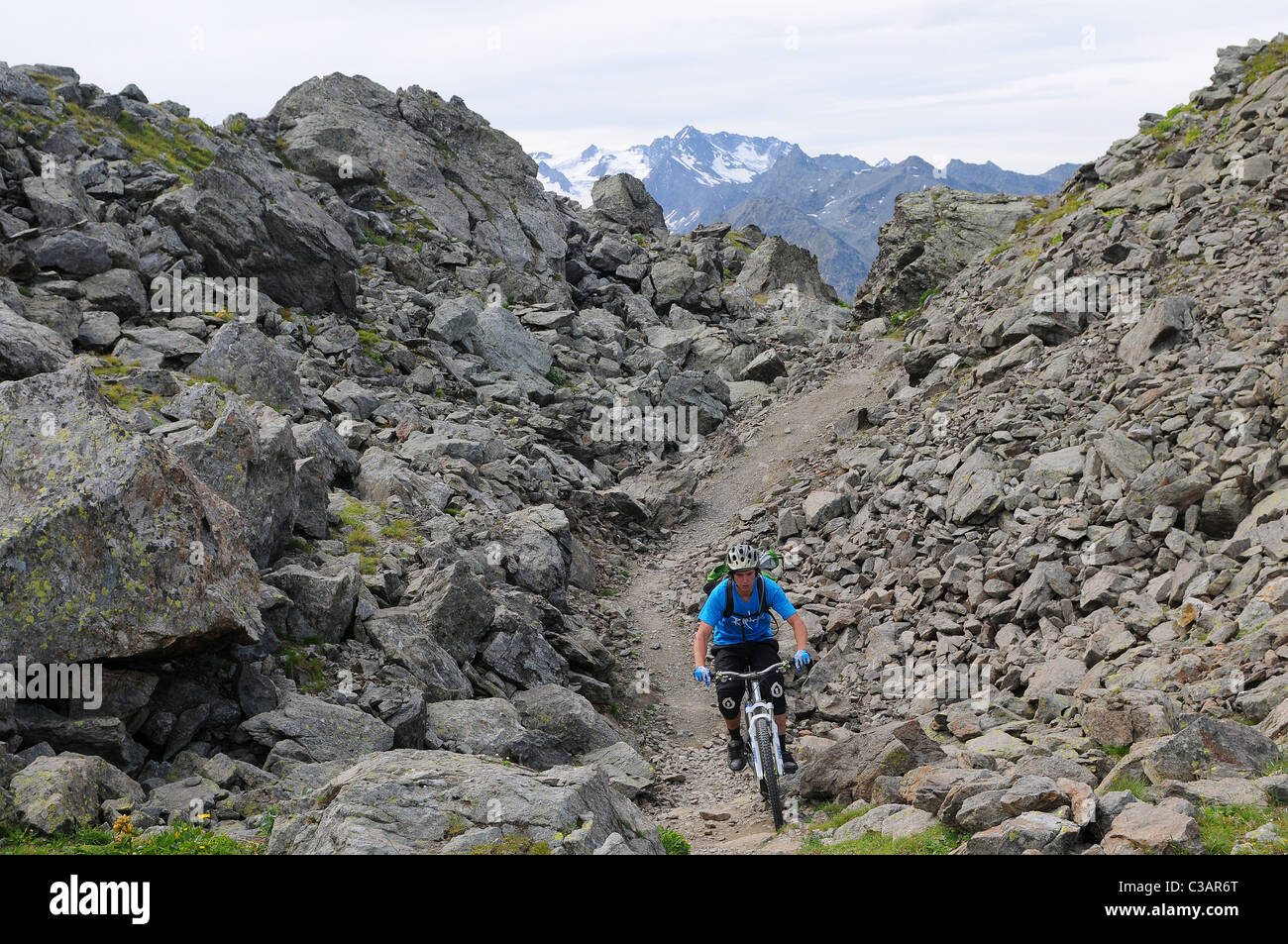 A mountain biker rides across rocky terrain at altitude in the French ski resort of Courchevel. Stock Photo