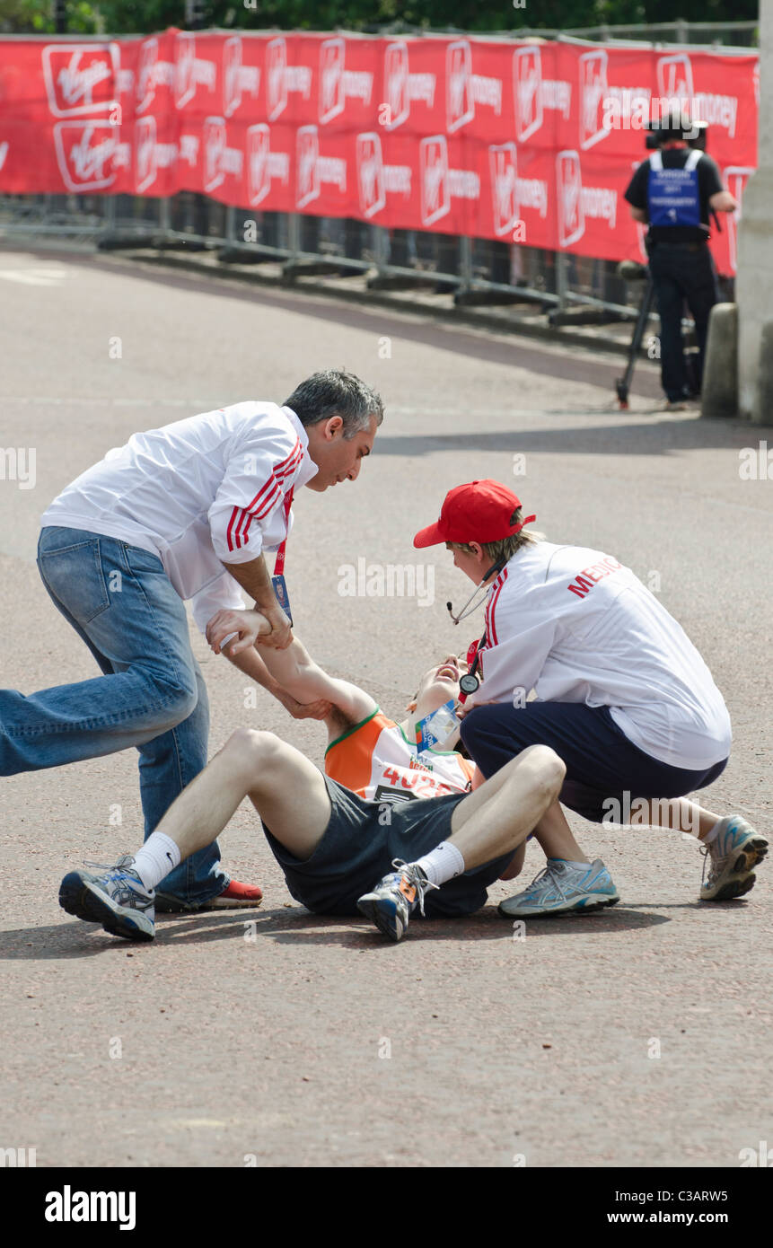 Collapsing competitor helped by  doctor at London marathon given Medical attention. London marathon 2011 Stock Photo