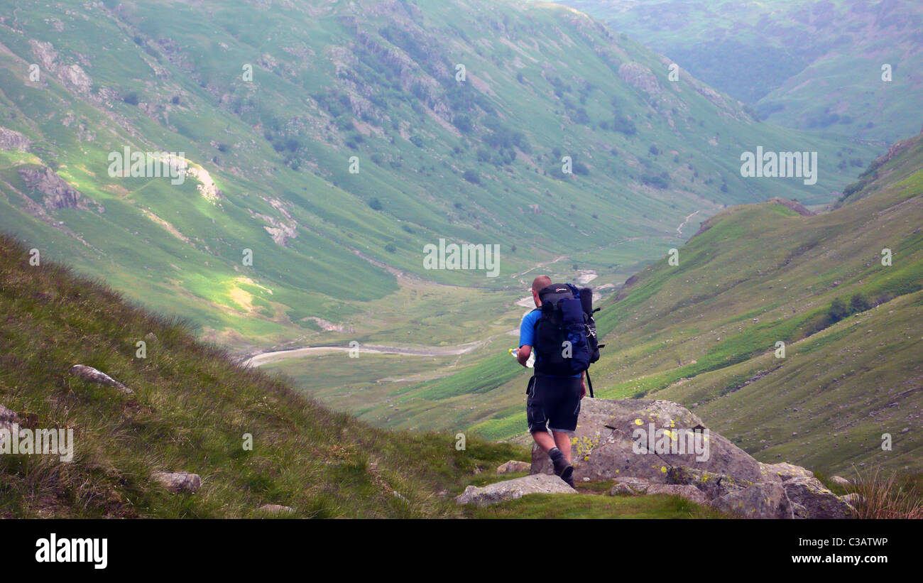 A Cumbria Way walker heading North on Stake Pass towards Langstrath Beck. Stock Photo