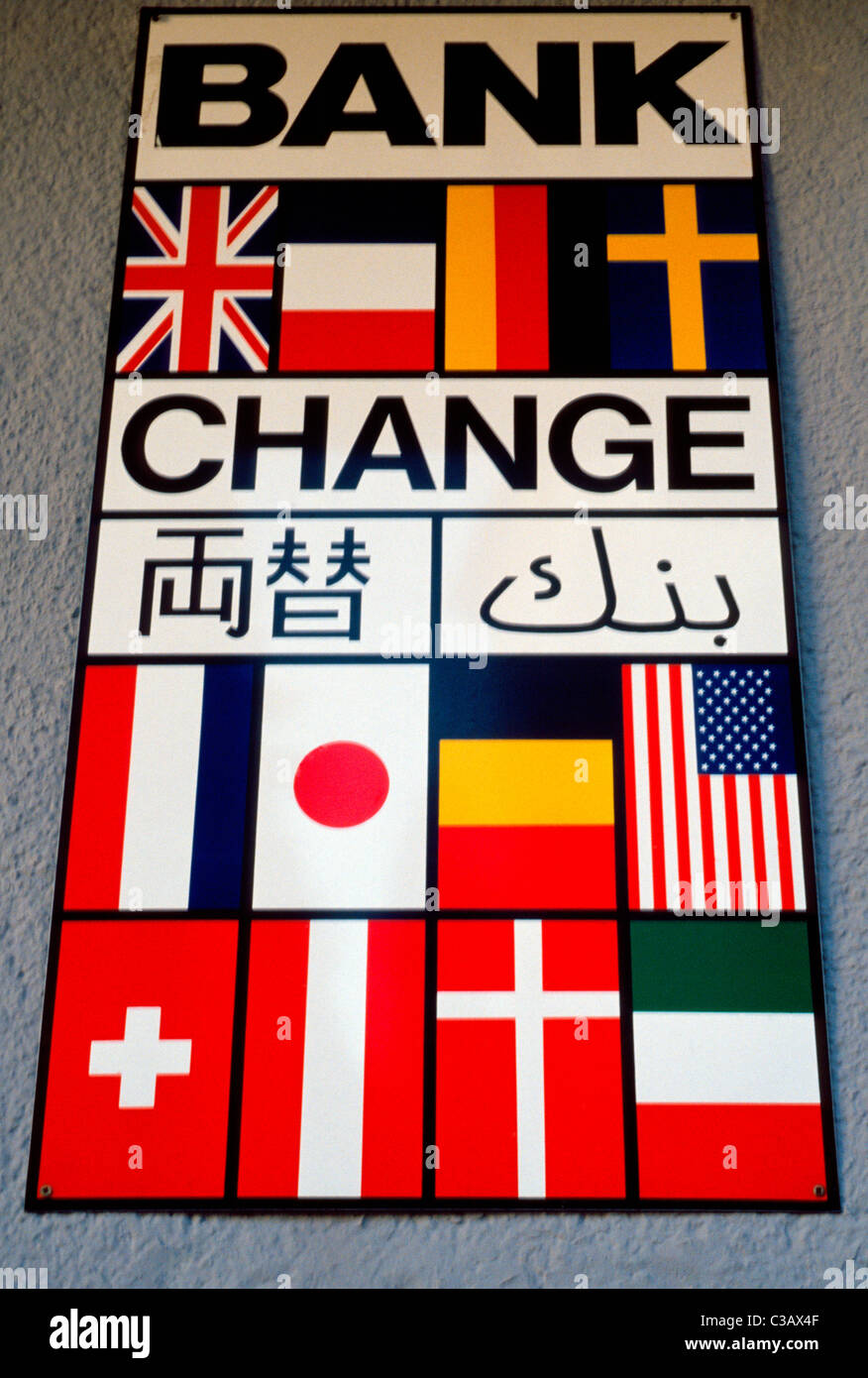 A sign with the flags of various countries indicates international money exchange is available inside a European bank in Austria. Stock Photo