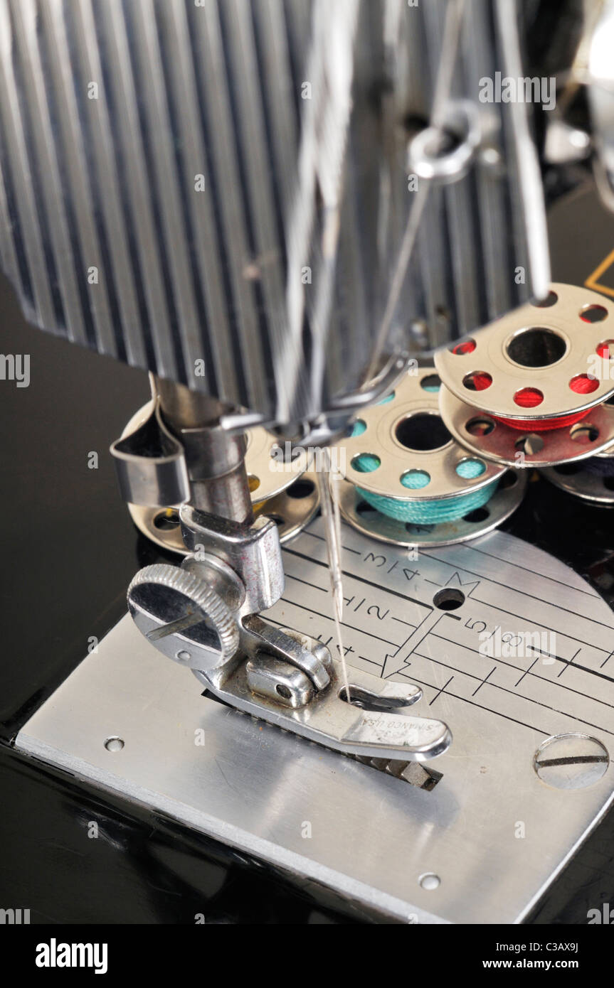 Threaded needle and bobbins spooled with thread of an antique Singer sewing machine close-up. Stock Photo