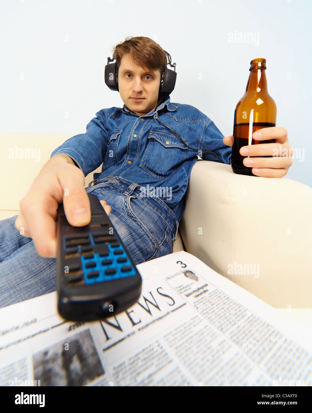 Young man sitting on the couch watching TV Stock Photo Alamy
