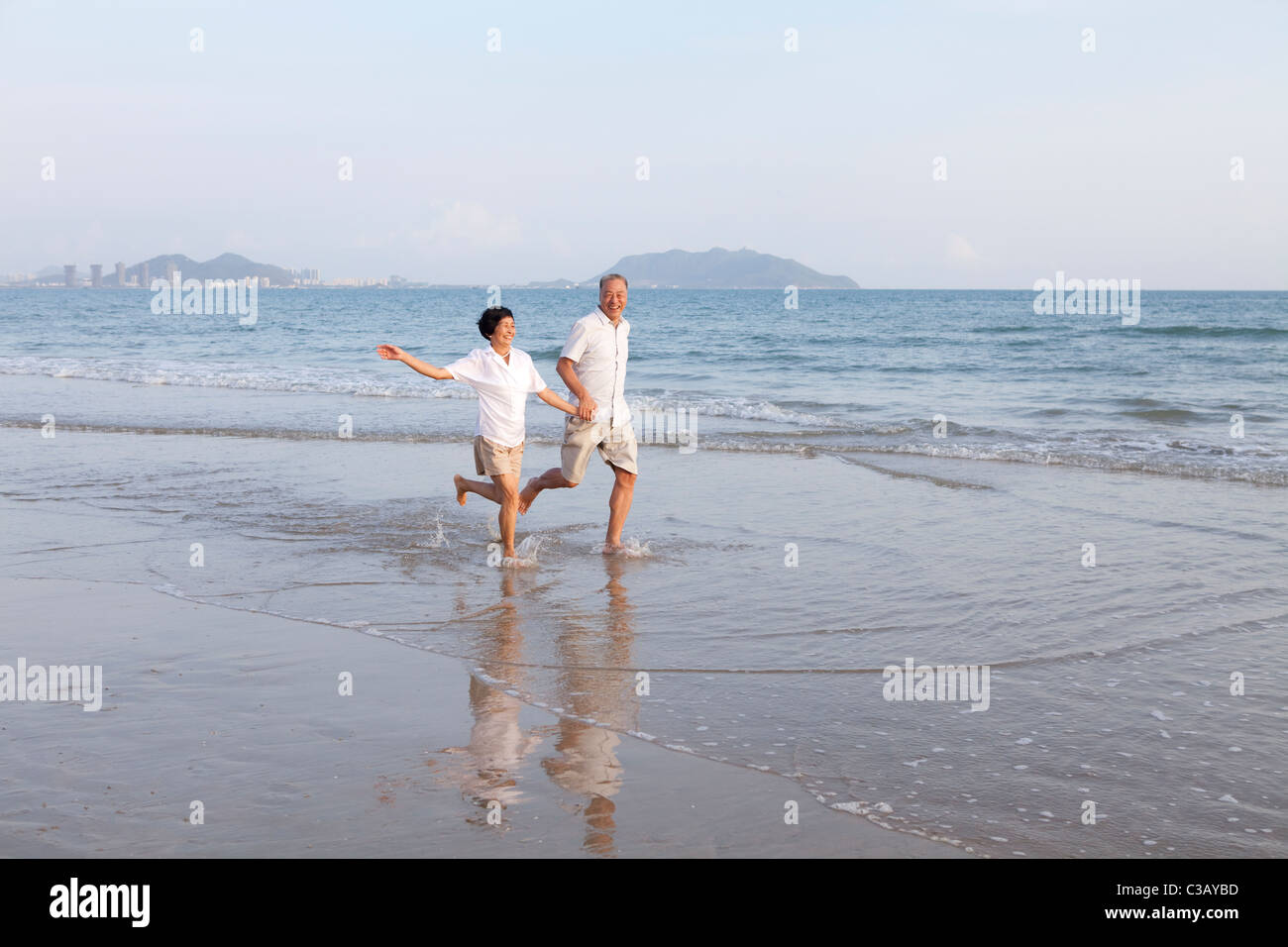 Portrait of a senior couple running at the beach Stock Photo
