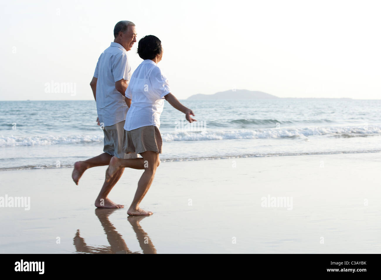 Happy senior couple running on the beach Stock Photo