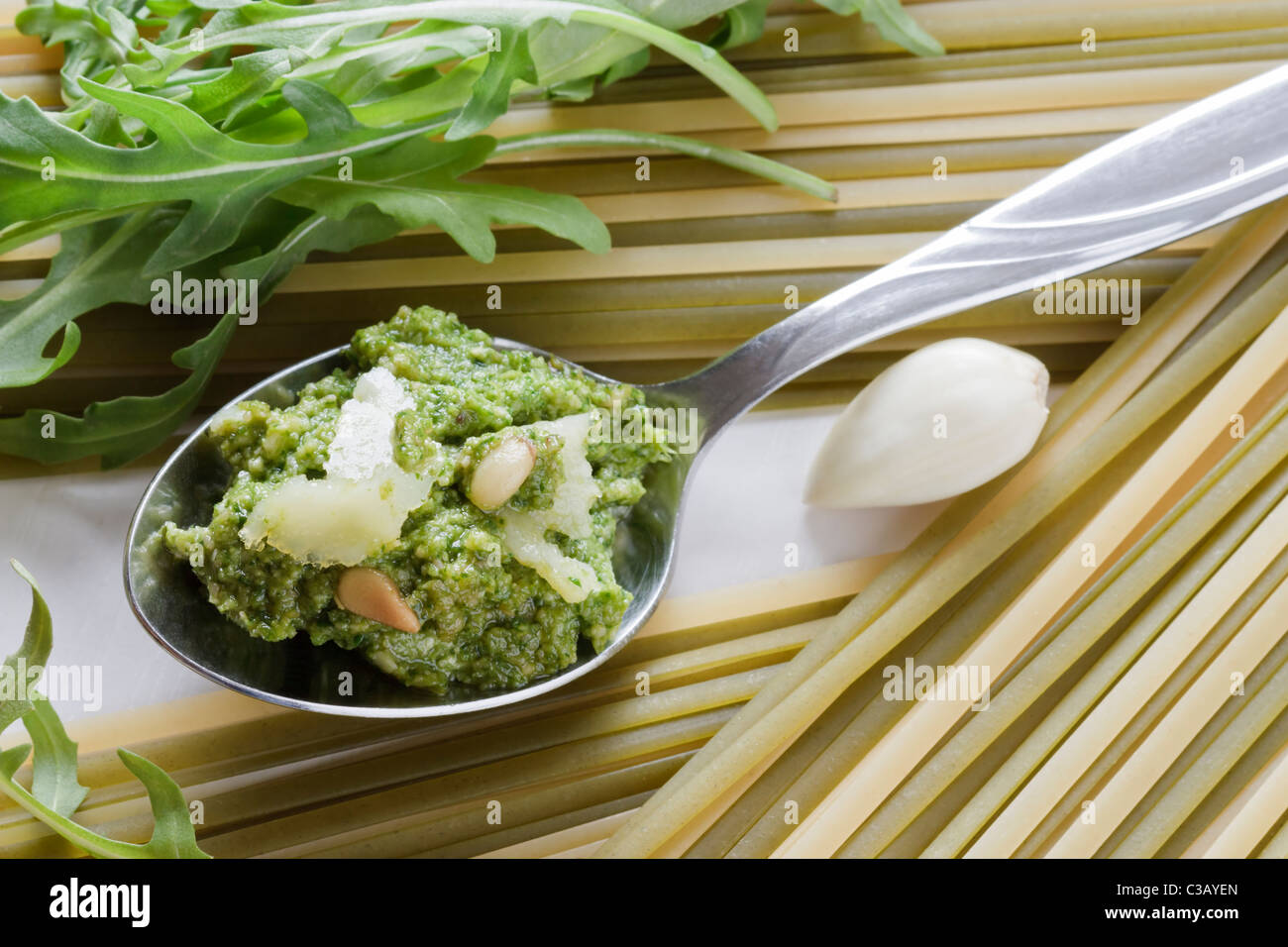 Spoon with fresh prepared rocket pesto, parmesan, pine nuts, garlic and linguine. Stock Photo