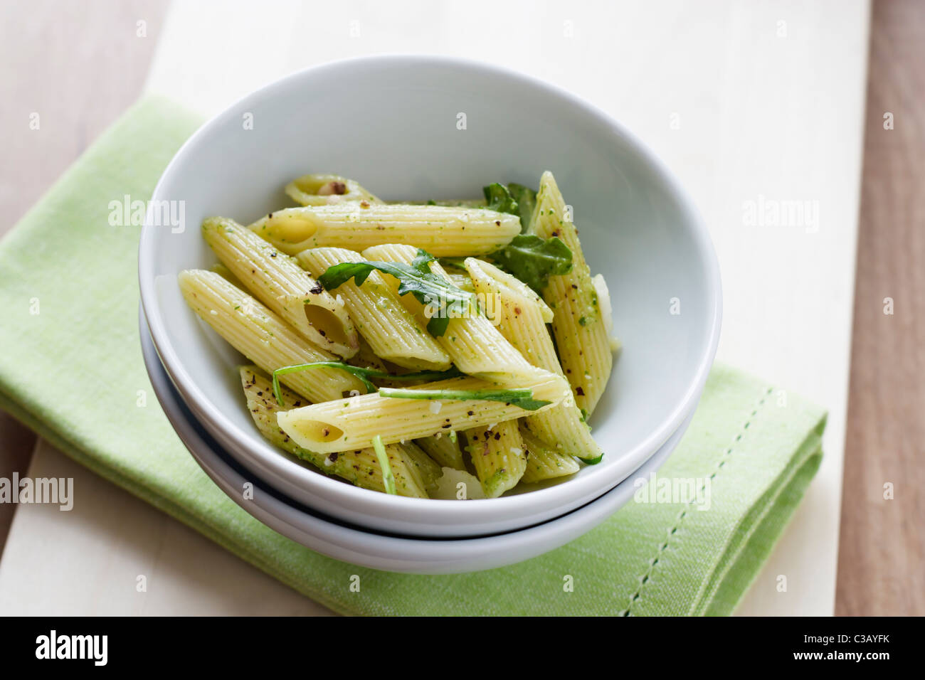 Rigatoni with home made rocket pesto, served in a white bowl on a green napkin. Stock Photo