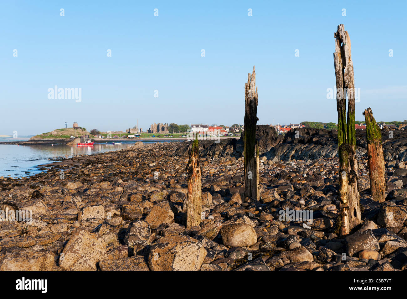 Lindisfarne shoreline with the remains of the old jetty in the foreground. Stock Photo