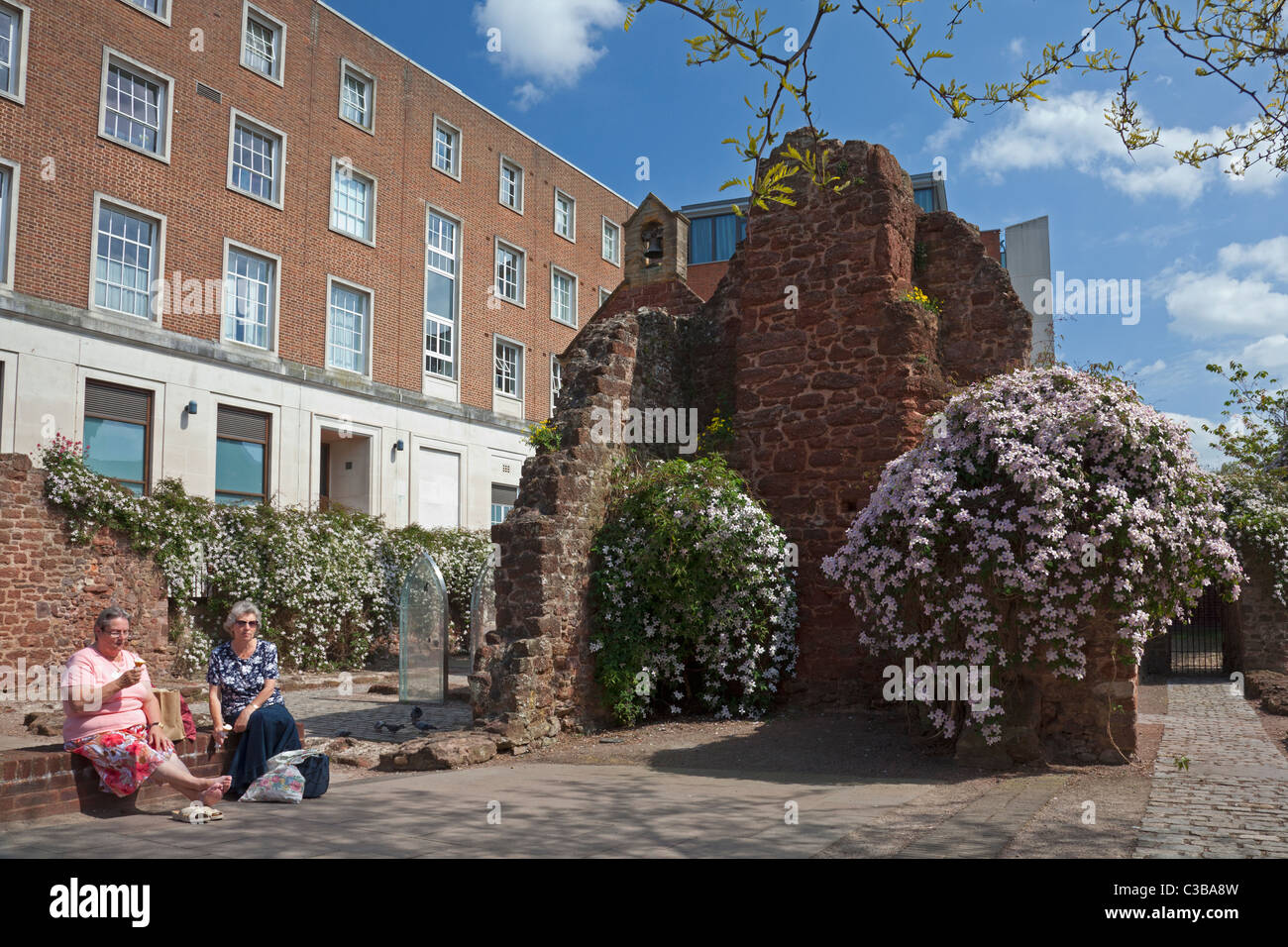 Two women enjoying an ice cream beside the ruins of the city walls, Exeter, Devon Stock Photo