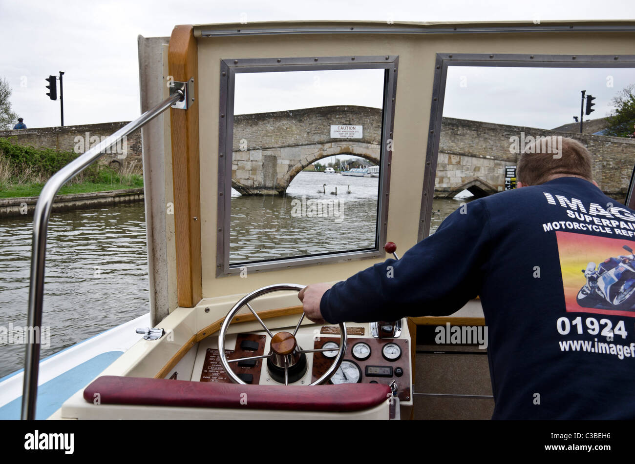Pilot steering a cruiser towards Potter Heigham Bridge on the River
