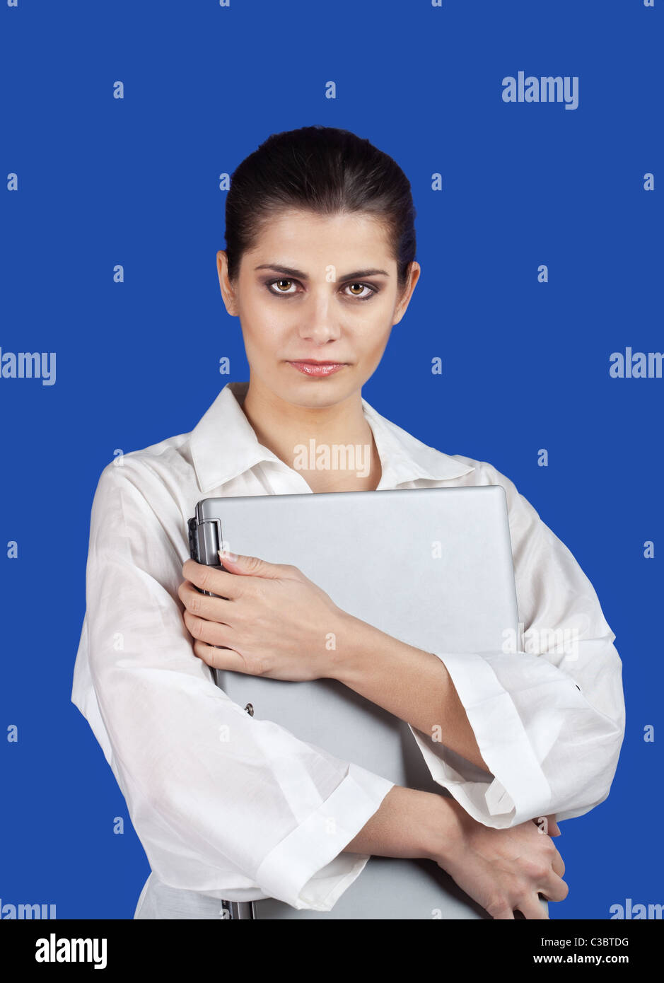 Serious young brunette woman embracing laptop computer Stock Photo