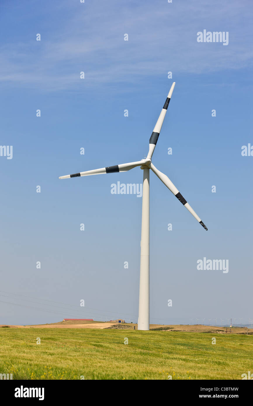 Windmill in green field over cloudy sky Stock Photo