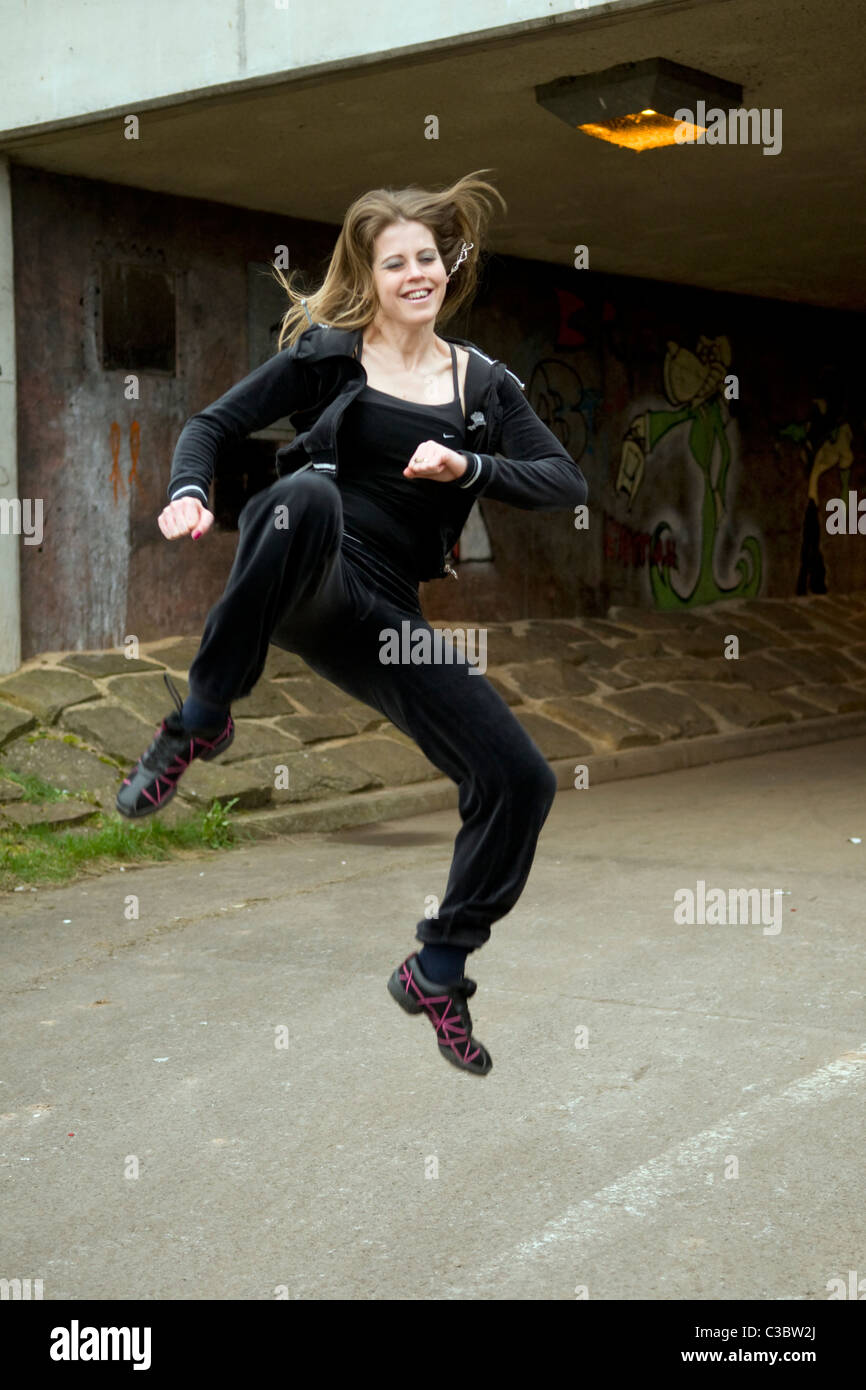 young Caucasian woman doing tae kwon do martial arts kicks in underpass near Emersons Green in Bristol uk Stock Photo