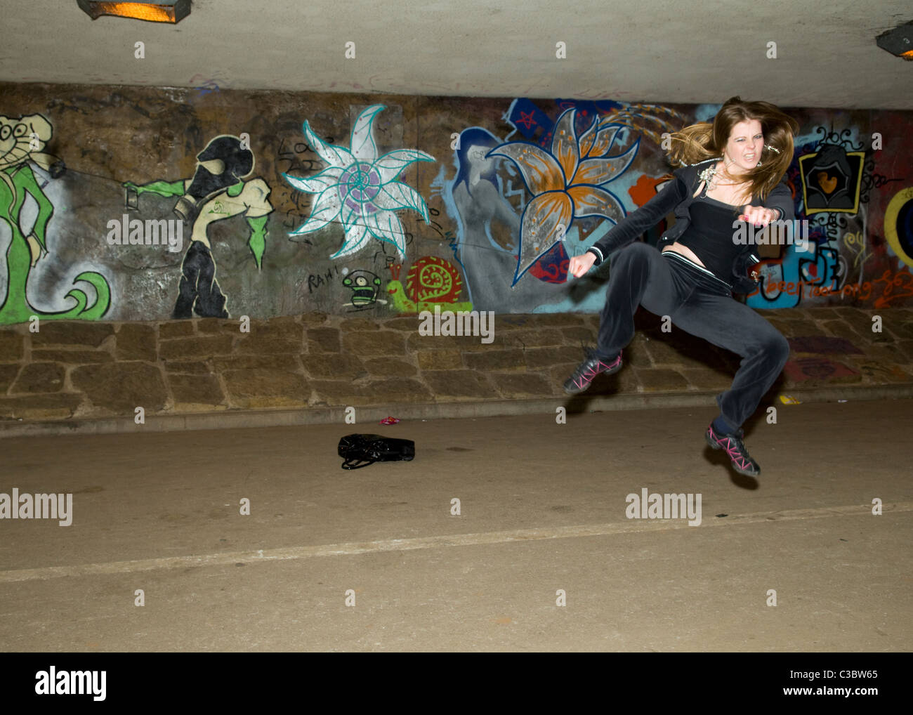 young Caucasian woman doing tae kwon do martial arts kicks in underpass near Emersons Green in Bristol uk Stock Photo