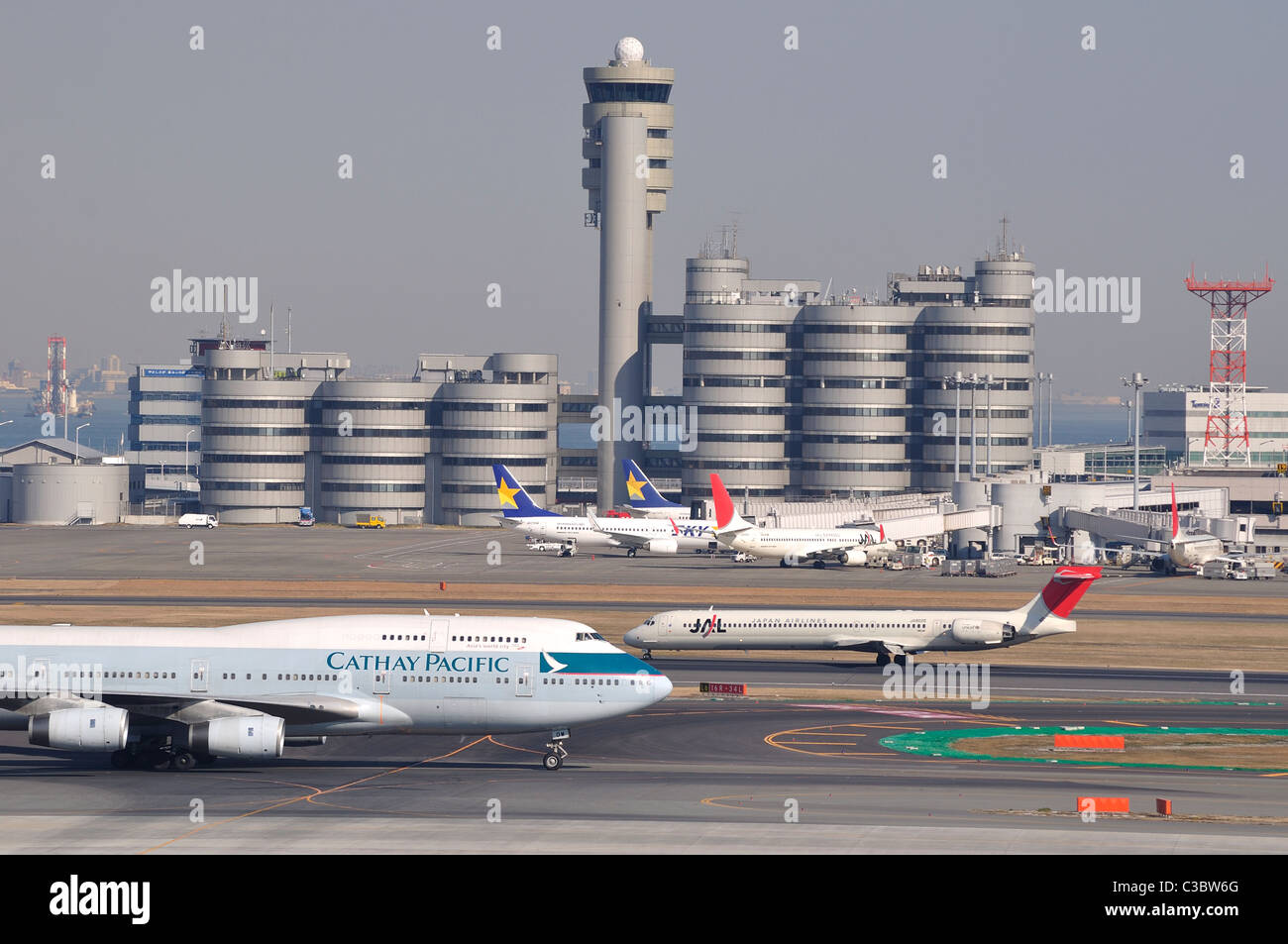 Aircraft / airplanes on the tarmac with tower in background at 'Haneda' Tokyo International Airport (Japan) Stock Photo