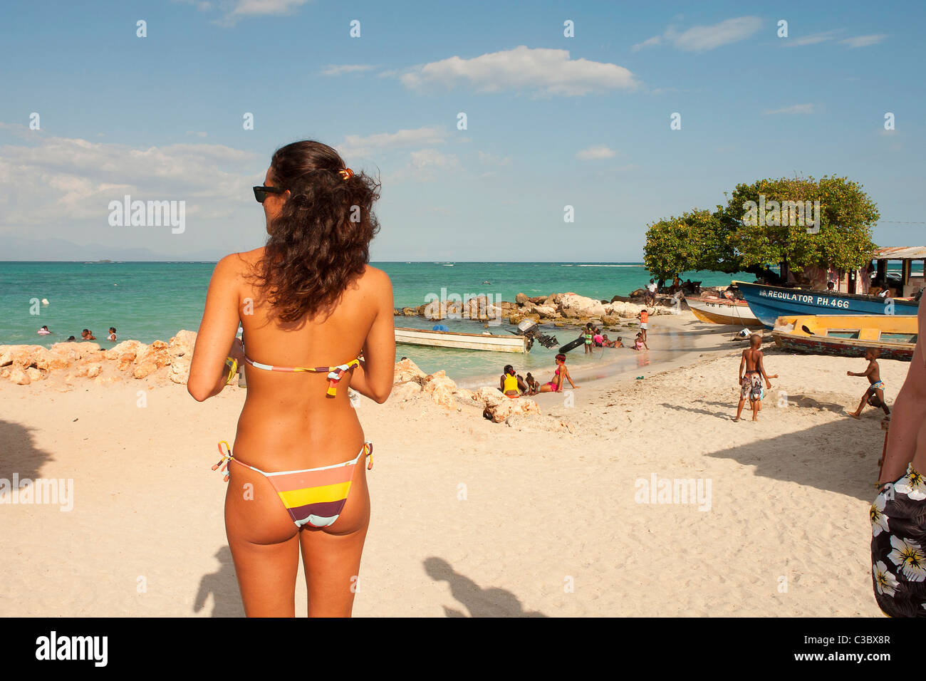 A brunette woman in a skimpy bikini on looks out across the Caribbean sea from Hellshire beach. Stock Photo
